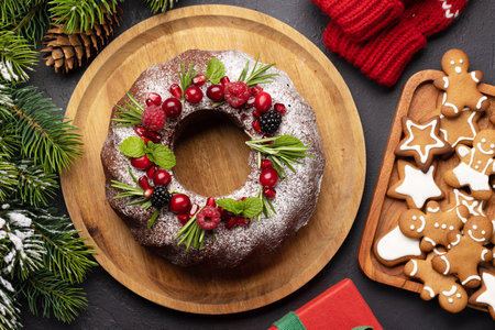 Christmas cake decorated with pomegranate seeds, cranberries and rosemary. flat lay