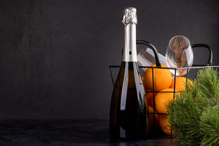 Basket with oranges, champagne and fir tree branch. Christmas gift with copy space for your greetingsの写真素材