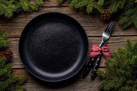 Table setting from above with empty plate, Christmas Fir tree branches and pine cones on wooden background. flat layの写真素材