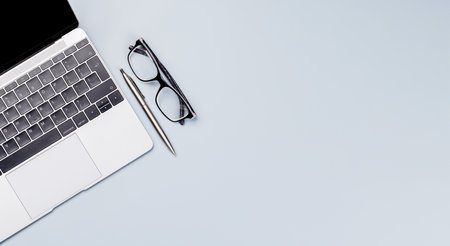 Top view business office desk with laptop, office supplies and eyeglasses. Flat lay workspace with sunny light and copy spaceの写真素材
