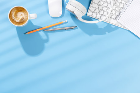 Top view business office desk with keyboard, office supplies and coffee. Flat lay workspace with sunny light and copy spaceの写真素材