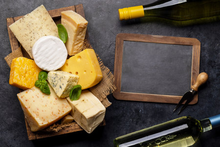 Various cheese in box and wine bottles. Flat lay with chalk board for copy spaceの写真素材