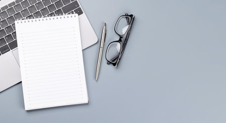 Top view business office desk with laptop, office supplies and eyeglasses. Flat lay workspace with sunny light and copy spaceの写真素材