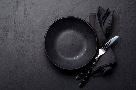 Empty plate with fork and knife on dark stone table. Flat lay with copy spaceの写真素材