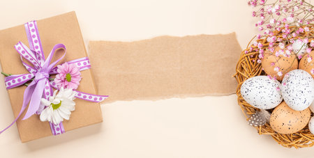 Gift box, Easter eggs and flowers on a beige background with space for your greetings. flat lay