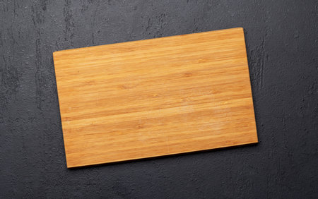 Wooden cutting board on stone kitchen table. Flat lay with copy space