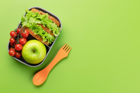 School lunch box on green background. education and nutrition. Flat lay with blank spaceの写真素材