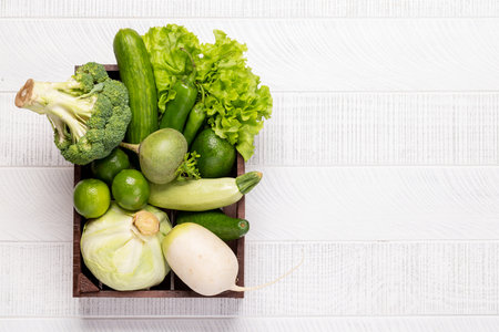 Wooden box full of healthy green vegetables and fruits. Flat lay with copy spaceの写真素材
