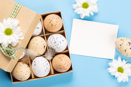 Gift box, Easter eggs and flowers on a blue background with space for your greetings. flat layの写真素材