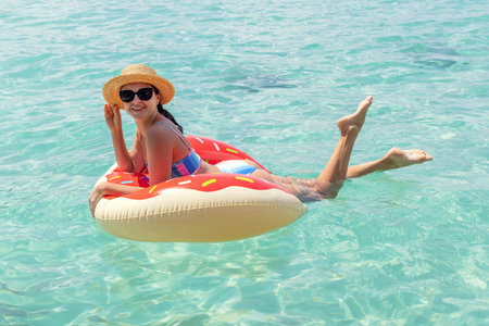 Beautiful young woman with inflatable donut ring relaxing in the sea. summer holidays