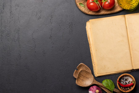 Top-down view of a kitchen table with ingredients, utensils, and an open cookbook with empty pages, perfect for creating a mockup for recipes or menusの写真素材
