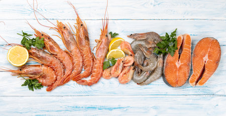 Fresh seafood such as shrimp, langoustines and trout steaks. Flat lay on blue wooden tableの写真素材