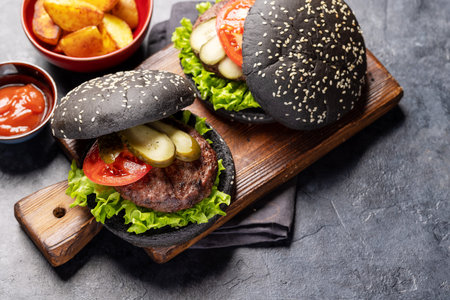 Homemade beef burgers with black buns and french friesの写真素材