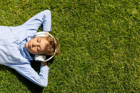 A boy relaxing on the grass, listening to music with headphones. flat layの写真素材