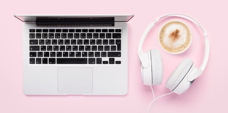 Laptop, headphones and coffee cup on pink background. flat layの写真素材