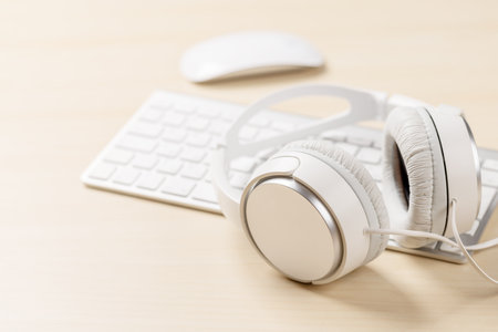 Workspace with keyboard, mouse, and headphones on desk, with empty space for creativityの写真素材