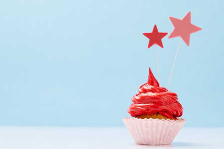Red cream cupcake with decor on blue background with copy spaceの写真素材
