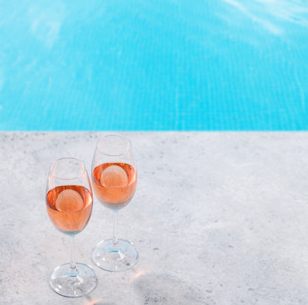 Refreshing rose wine by the pool on a sunny day, the perfect summer vacation. View from above with...