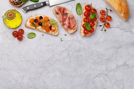 A delectable sandwich set of bruschetta adorned with juicy tomatoes, cheese, and savory prosciutto. Flat lay with copy spaceの写真素材
