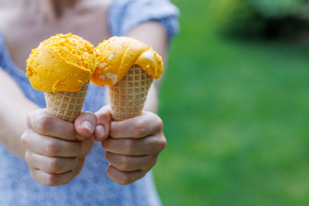 Woman's hands holding refreshing ice cream in waffle cones treats with a hint of zesty lemon flavor....
