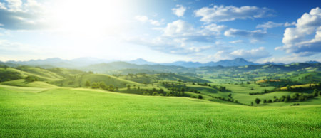 Idyllic landscape featuring a green meadow and majestic snowy mountains in the backgroundの写真素材