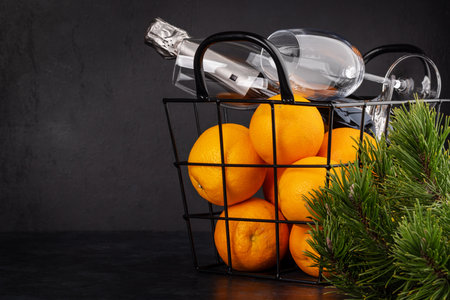 Basket with oranges, champagne and fir tree branch. Christmas gift with copy space for your greetingsの写真素材