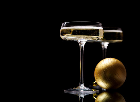 Two champagne glasses and Christmas bauble on a black backgroundの写真素材