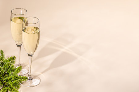 Two champagne glasses on a beige background with copy space. Christmas greeting card templateの写真素材