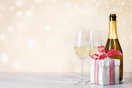 Two champagne glasses and gift box. Christmas greeting card template with copy spaceの写真素材