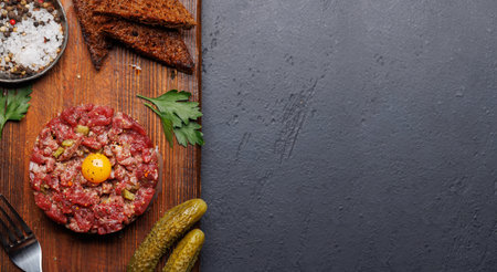Savory beef tartare with pickled gherkins and brown bread toasts. Flat lay with copy spaceの写真素材