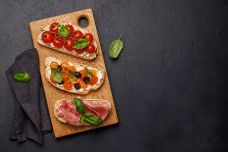 A delectable sandwich set of bruschetta adorned with juicy tomatoes, cheese, and savory prosciutto. Flat lay with copy spaceの写真素材