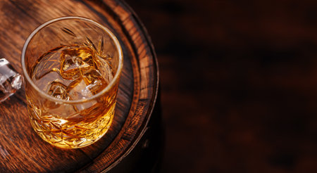 Whiskey glass with ice on a rustic barrel, a classic sip. With copy spaceの写真素材