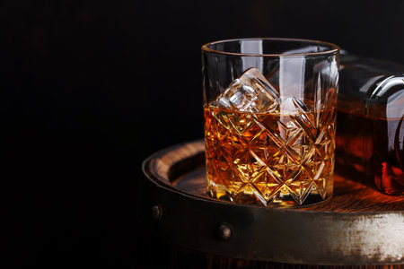 Whiskey glass with ice on a rustic barrel, a classic sip. With copy spaceの写真素材