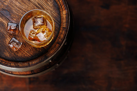 Whiskey glass with ice on a rustic barrel, a classic sip. With copy spaceの写真素材
