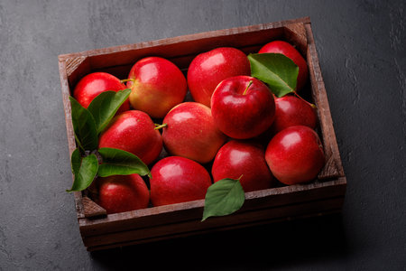 Wooden box with fresh red apples on stone tableの写真素材