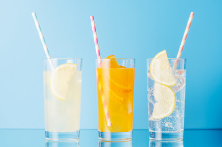 Various lemonade with ice in glasses over blue backgroundの写真素材