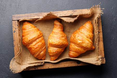Fresh croissants in wooden box. Flat layの写真素材