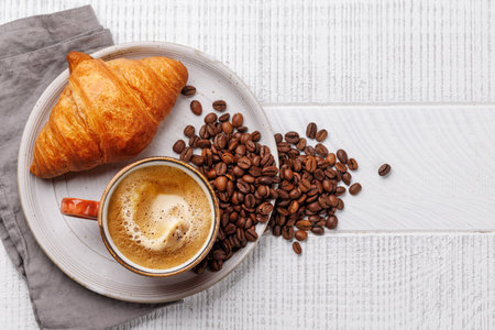 Cappuccino coffee and fresh croissant on wooden table. Flat lay with copy spaceの写真素材
