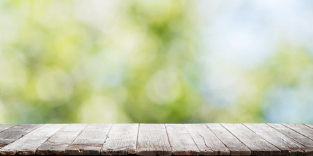 Empty wooden table over blurred sunny bokeh natural background with space for your productの写真素材