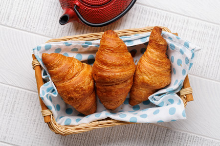 Teapot and fresh croissants in basket. Flat layの写真素材