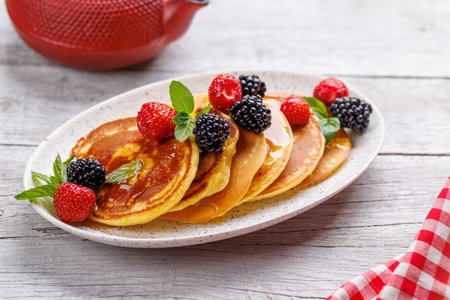 Tasty homemade pancakes with berries and honey syrupの写真素材