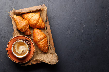 Cappuccino coffee and fresh croissants on stone table. Flat lay with copy spaceの写真素材
