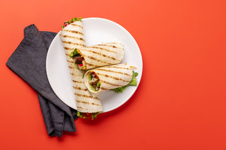 Mexican food featuring burritos with meat and grilled vegetables. Over red with copy spaceの写真素材