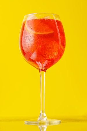 spritz cocktail with orange slice and ice on yellowの写真素材