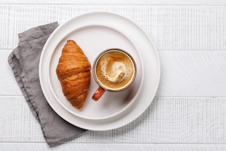 Cappuccino coffee and fresh croissant on wooden table. Flat lay with copy spaceの写真素材