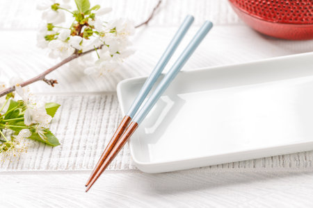 Table adorned with cherry blossom branch and chopsticks, epitomizing Japanese food culture, providing ample copy spaceの写真素材