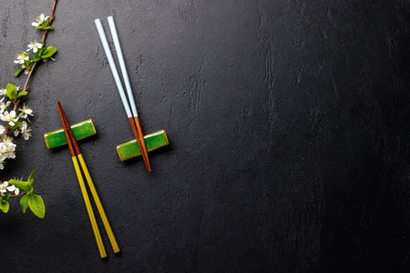 Table adorned with cherry blossom branch and chopsticks, epitomizing Japanese food culture, providing ample copy spaceの写真素材
