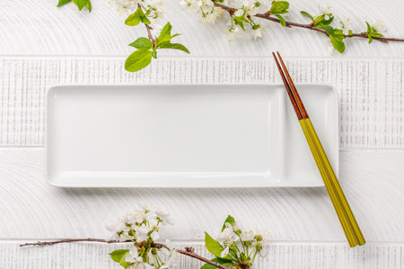 Table adorned with cherry blossom branch and chopsticks, epitomizing Japanese food culture, providing ample copy spaceの写真素材