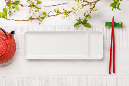 Table adorned with cherry blossom branch and chopsticks, epitomizing Japanese food culture, providing ample copy spaceの写真素材