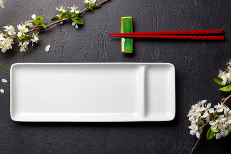 Table adorned with cherry blossom branch and chopsticks, epitomizing Japanese food culture, providing ample copy spaceの写真素材